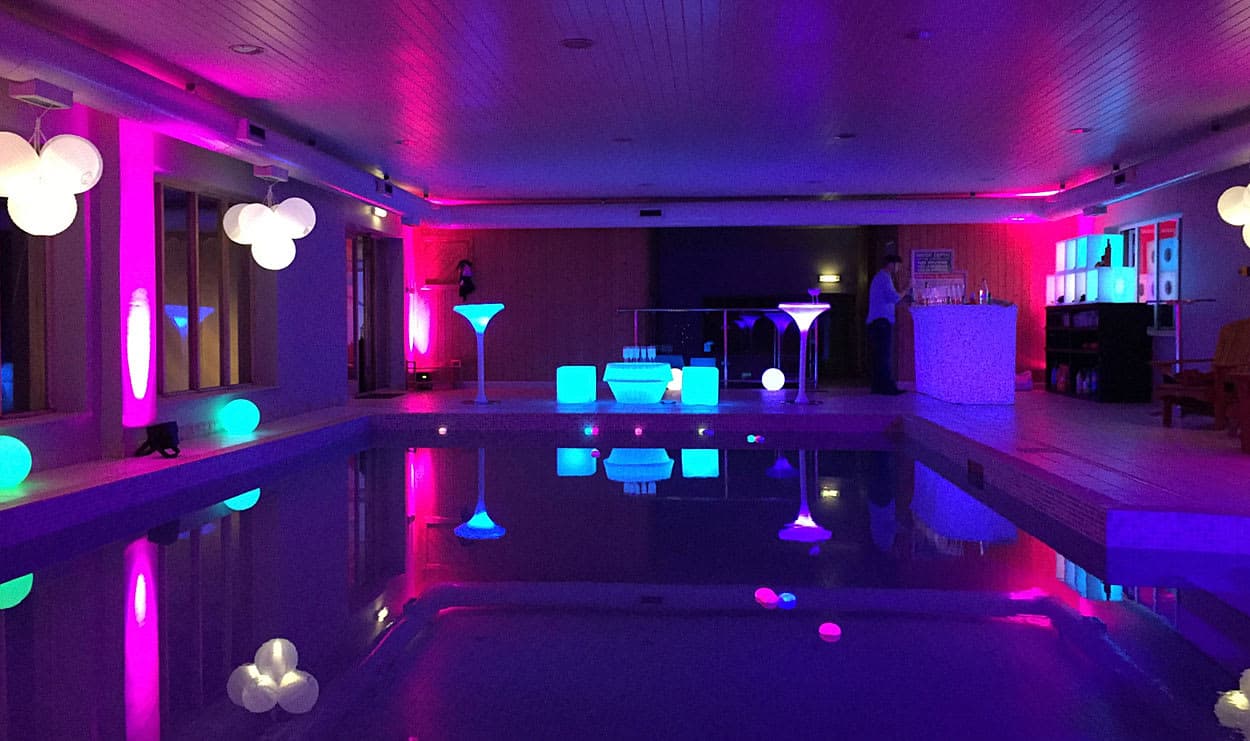Pool party with colourful lighting reflecting on the water for a stylish summer celebration