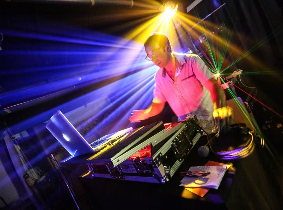 Party DJ with laser lighting effects creating a vibrant and energetic dance floor atmosphere