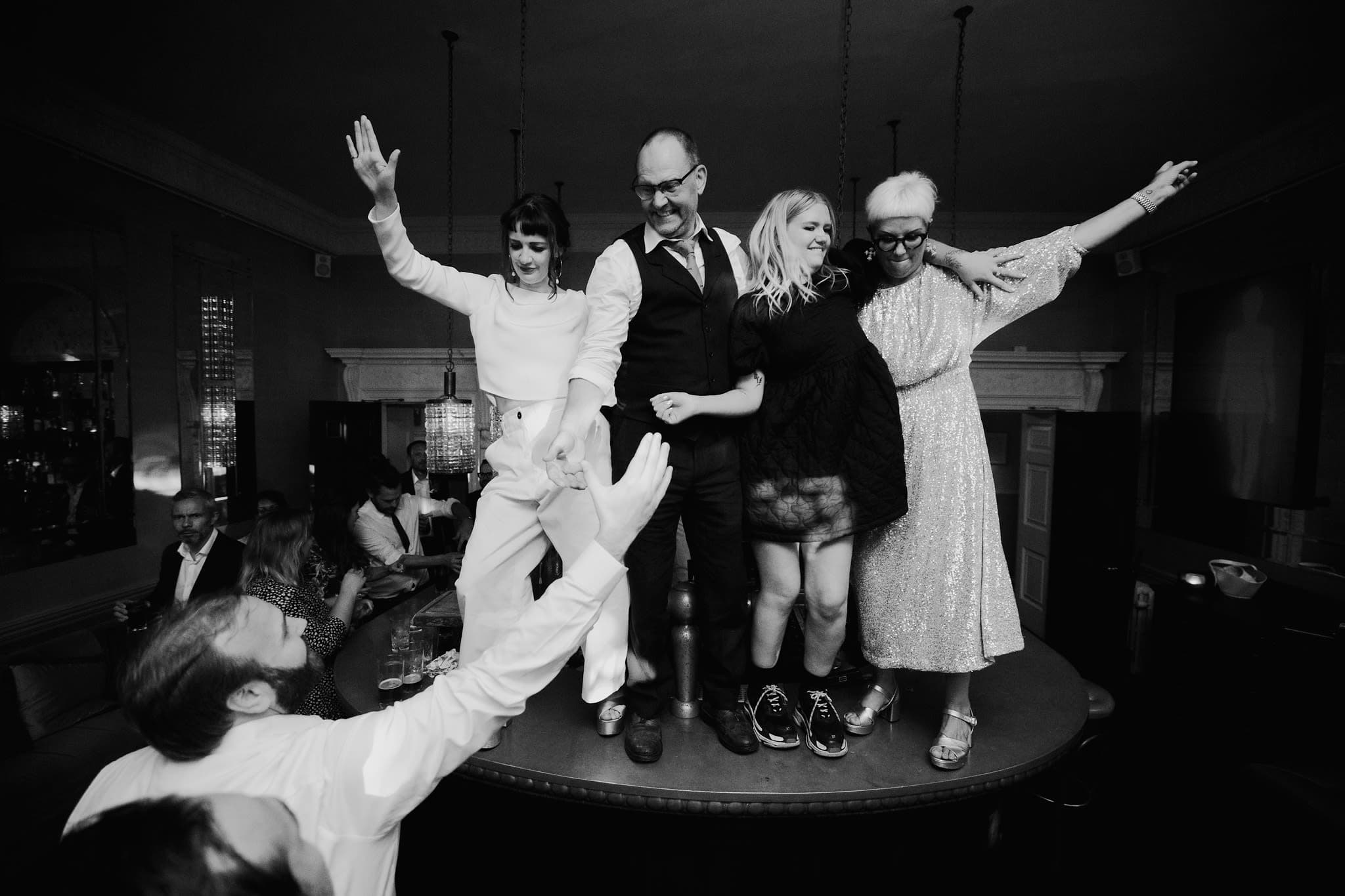Wedding guests dancing on the bar at Babington House with a packed dancefloor